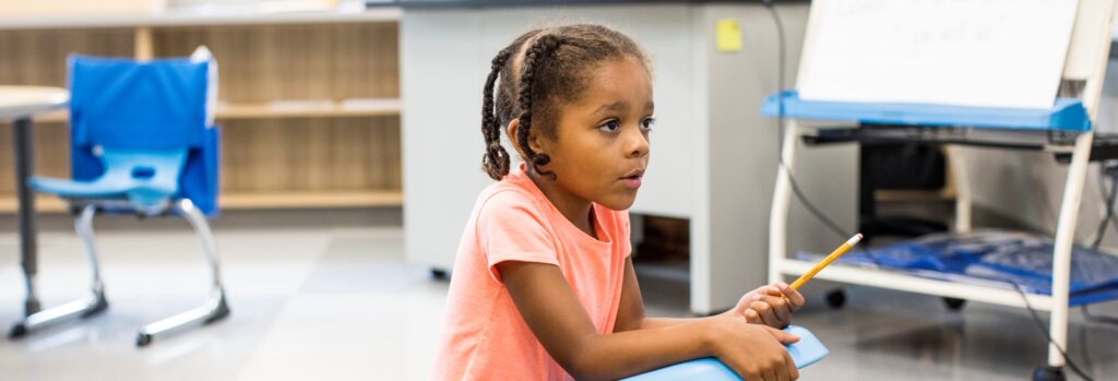 A young student playing on the floor of her classroom